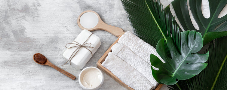 Spa: Articles de soins du corps sur blanc avec des feuilles tropicales.